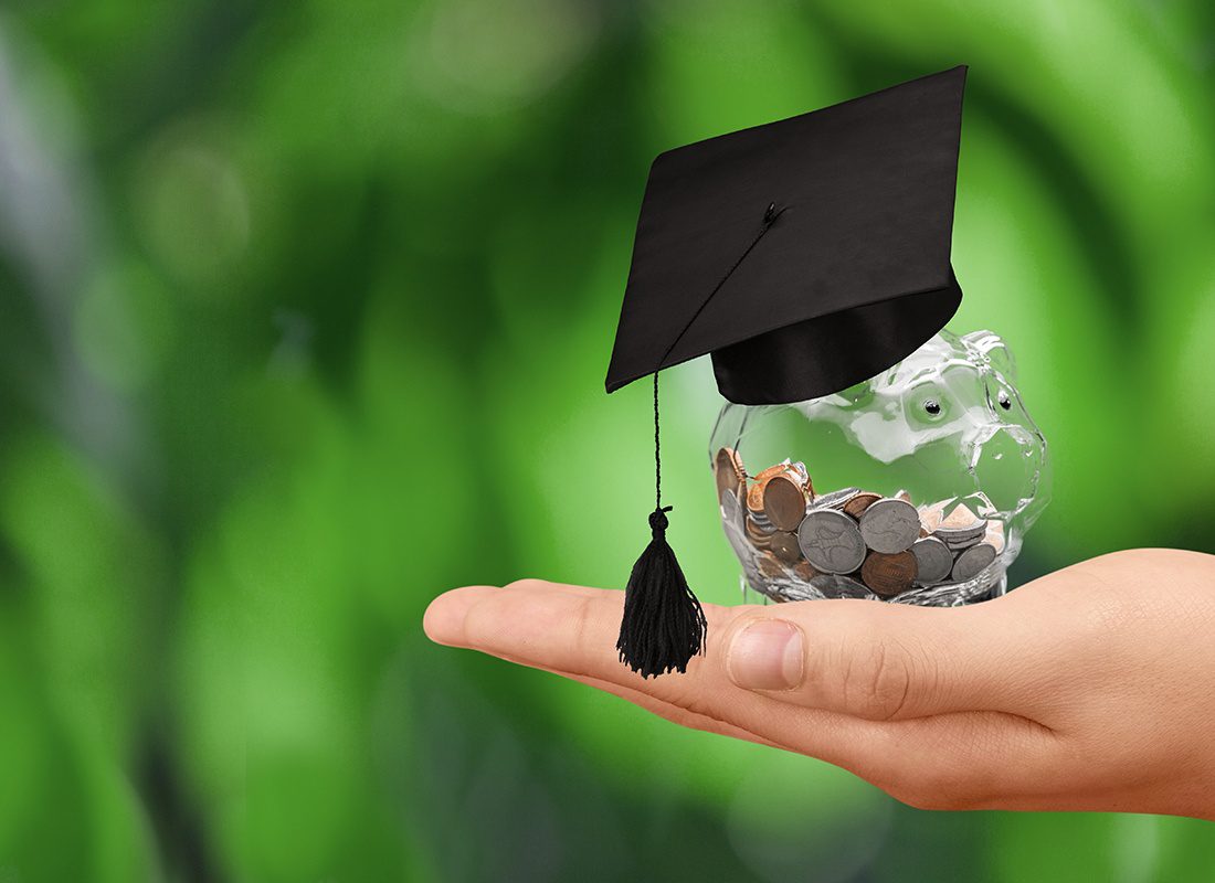 The Charles McClenahan Technical School Scholarship - Close-up of a Hand Holding a Glass Piggy Bank With a Cap Filled With Coins