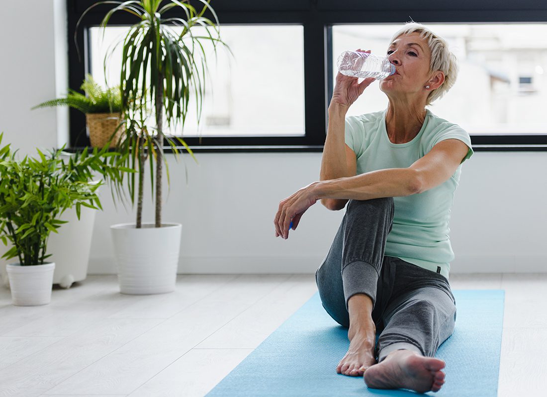 Life and Health Insurance - Elderly Woman Drinking Water After Doing Yoga